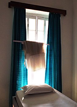 A bed by a tall window with green curtains