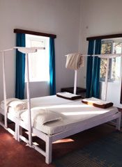 A twin room with white four-poster beds and green curtains