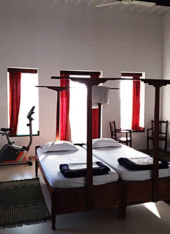 A twin room with four-poster beds and red curtains