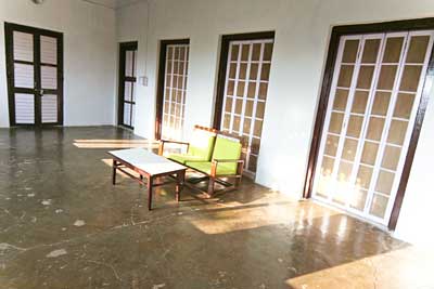 A sunlit hall with tall windows and chairs